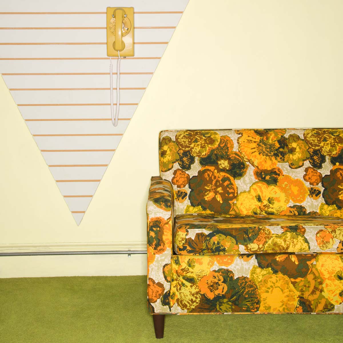 old floral couch and wall phone.