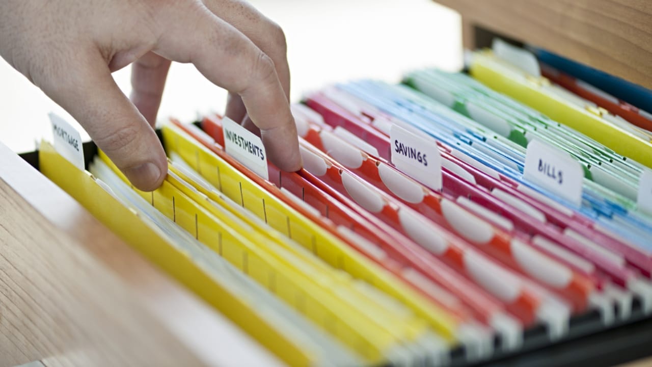 Declutter Your Home in a Flash with These 18 Everyday Items - hand searching through file folder ss136964447